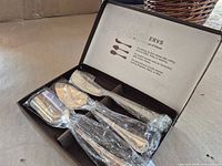 Box opened displaying three silver-plated cheese utensils in plastic wrap