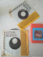 Overview showing two 45s in Dunhill sleeves and one 8-track cartridge