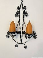 Front view wrought iron two-light sconce with both candles in holders