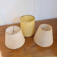 Group of three fiberglass lamp shades on wooden surface