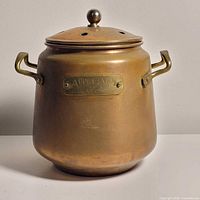 Front view showing pot with lid, brass handles, copper finish