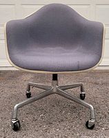 Front view of upholstered fiberglass shell chair on aluminum base with casters