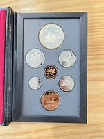 Open case showing seven coins in capsules