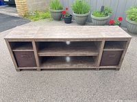 Full front view of TV stand with two fabric bins and centre shelving