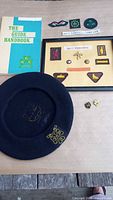 All items overview: handbook, beret, frame of badges, loose patches and pins
