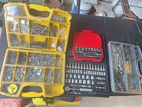 Overview of three organizers on table: yellow fastener box, black/red socket set, grey wrench organizer