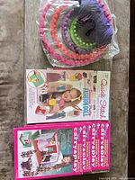 Stacked plastic knitting looms with purple yarn plus pattern booklets