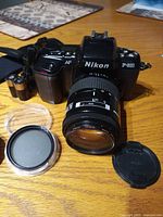 Front view Nikon F-601 with attached zoom lens, filter, cap visible