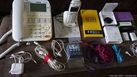 Full lot overview showing VTech phone base, cordless handset, chargers, cables, screen protector, TikTok ring