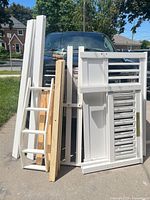 Multiple white bed components leaning against vehicle