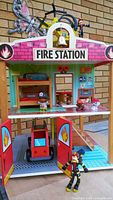 front view of fire station with vehicles, figures, furniture visible