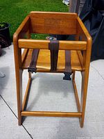 Front view of solid wood high chair showing seat, straps, finish