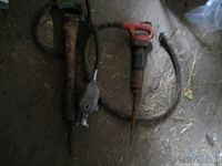 Two pneumatic jackhammers lying on floor, hoses visible