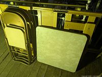 Folded metal chairs and square folding table leaning together