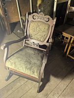Full view of rocking chair angled, showing carved frame and upholstery