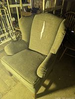 Front view of upholstered wingback armchair showing tear on backrest