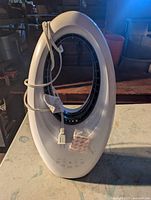 Full front view of white oval bladeless fan with cord