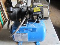 Full view of Everbilt pump mounted on blue pressure tank with fittings and hose