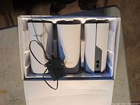 Three TP-Link Deco units and power adapter in box