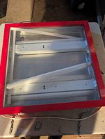 Red-framed illuminated sign case with fluorescent tubes inside