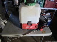 Front view of Milwaukee backpack sprayer with wand on table