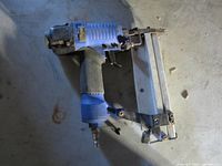 Blue pneumatic brad nailer on work surface