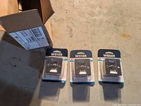 Three Weiser sliding door locks in packaging beside shipping box