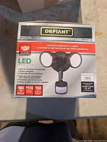 Front of boxed Defiant LED motion security light showing model and specifications
