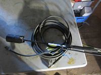Propane torch wand, hose coiled, regulator fitting visible