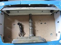 Metal table lamp inside box with cord visible