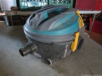Full view of Tennant V-CAN-12 vacuum showing body, wheels, suction port, handle and cord