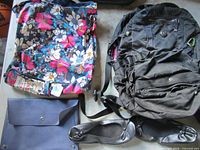 Group shot of floral tote, black backpack, navy clutch, black flats