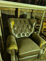 Front view of brown leather recliner showing tufted back, seat, arms, and wear