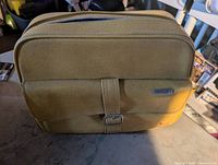 Front view of mustard yellow Samsonite vinyl bag with flap pocket and strap