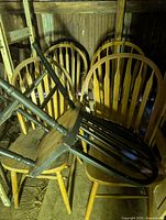 Front view showing upside-down dark spindle-back chair atop natural oak chairs