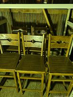 Front view of all five wooden stools showing backs, seats and finish