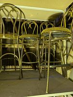 Four gold-tone metal bar stools on shelving
