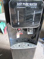 Front view of Just Pure Water dispenser showing faucets and branding