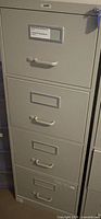Front view of beige four-drawer metal vertical filing cabinet with handles, label holders, and lock