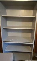 Front view of gray laminate five-shelf bookcase showing shelves and wear