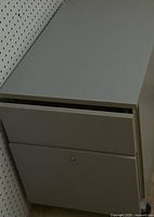 Gray metal two-drawer lateral file cabinet showing top and drawers, keyed lock visible