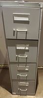 Front view of gray metal four-drawer vertical filing cabinet with lock