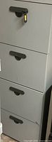 Front view of gray metal 4-drawer filing cabinet with key in lock