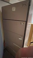 Front view of five-drawer tan metal filing cabinet showing overall style and condition