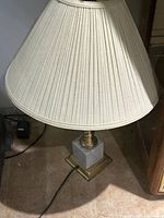 Full view of lamp showing brass body, gray marble base, ivory pleated shade