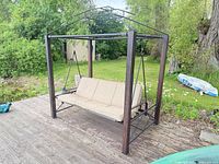 Full view of porch swing showing metal frame, canopy support, cushions