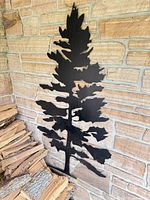 Full view of black metal tree silhouette mounted on stone wall