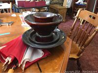 Overall view of the vintage brown ceramic insulator sitting on a wooden table with a red and white cloth.