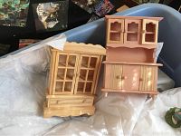 Two wooden dollhouse furniture pieces placed inside a blue plastic bin on top of white packing paper