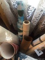 Photo showing close-up view of wrapping paper rolls inside ceramic crock near lace curtain.